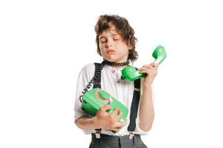 One little cute kid in retro style outfit, fashion of 70s, 80s years using retro phone isolated on...