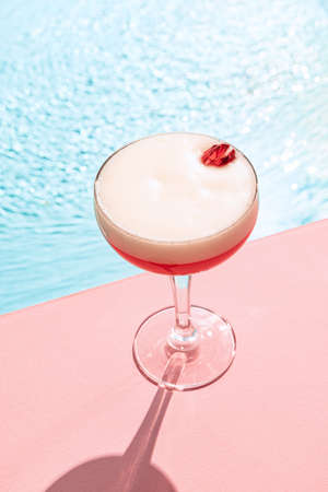 Clover club. Cold drink on a hot summer day. Cocktail glass near swimming pool over blue sky...