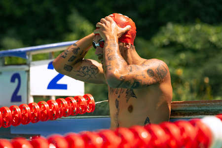 At swimming pool. Handsome man, swimmer in swimming cap and goggles training at open public pool. Vacation, active lifestyle, power, energy, sportの写真素材