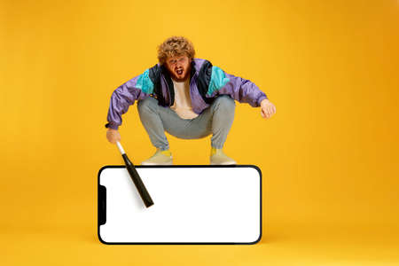 Emotional man, hipster standing on huge 3d model of cellphone with blank white screen isolated on...
