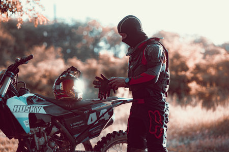 Mans silhouette, motocross rider on motorbike admiring the sunset at summer day evening, outdoors. Motocross sport, hobby, professional occupationのeditorial素材