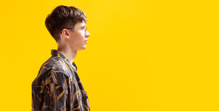 Profile view of handsome young man isolated on bright yellow studio backgroud. Human emotions,...