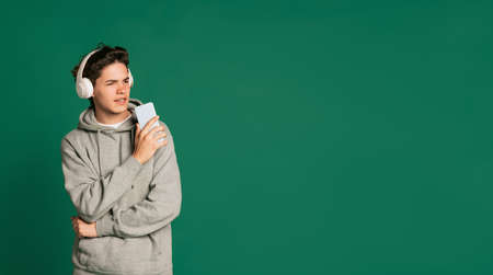 Portrait of expressive young boy, teen in casual style clothes posing isolated over green studio...