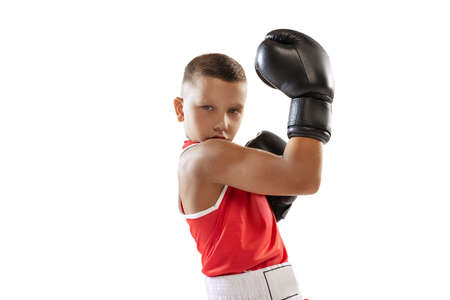 Portrait of active boy, beginner boxer in sports gloves and red uniform isolated on white background. Concept of sport, movement, studying, achievements, lifestyle.の写真素材