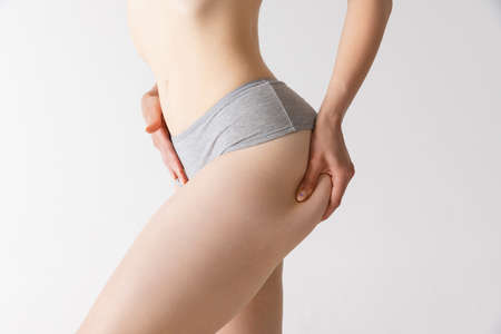 Cropped image of fit, tonned female body, buttocks in comfortable cotton underwear isolated over grey studio backgroundの写真素材
