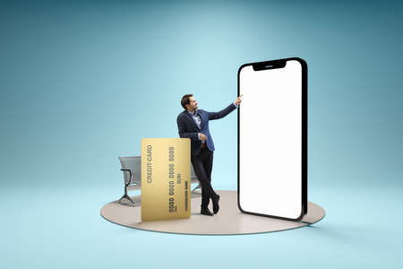 Young man, businessman standing in front of 3d model of cellphone with blank white screen isolated on blue background. Online shopping, payment, new app or website,の写真素材