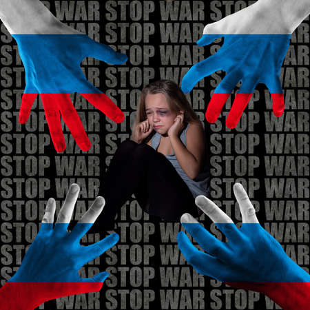 Conceptual collage with little scared child in fear and huge hands painted in white-blue-red colors isolated over dark background with lettering. Stop war in Ukraine conceptの写真素材