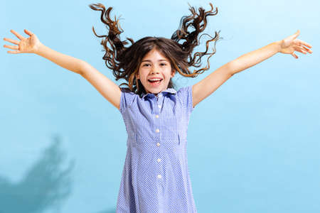 Portrait of winsome little girl,school age kid in summer dress isolated over blue background....