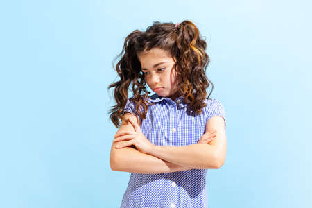 Portrait of winsome little girl,school age kid in summer dress isolated over blue background. Concept of children emotions, fashion, beauty, school and adの写真素材