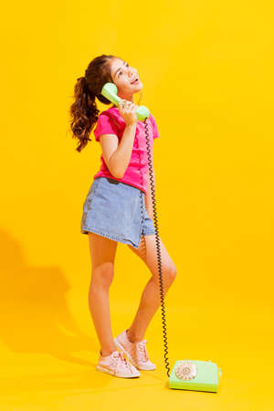Emotional little girl, kid in casual style clothes isolated over bright yellow background. Concept of children emotions, fashion, beauty, school and ad, retro styleの写真素材