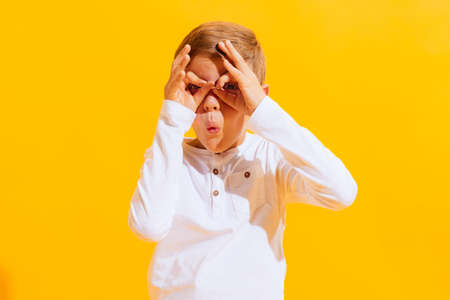 Portrait of cute little boy, happy kid having fun isolated on bright yellow background with. Concept of child emotions, facial expression, fashion and ad.の写真素材