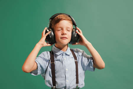 One preschool boy, kid wearing retro style outfit isolated on dark green background. Concept of emotions, facial expression, fashion, vintage and ad.の写真素材