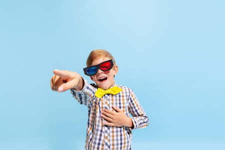 Emotional preschool boy, kid wearing retro style outfit and 3d glasses isolated on light blue...