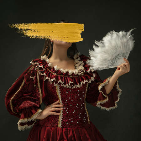 Young woman wearing historical outfit with yellow stroke of paint on her face. Contemporary artwork....