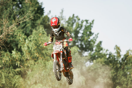 Dnipro, Ukraine JULY 01, 2022. Ukrainian beginner motorcycle rider driving on Enduro motorbike, outdoors at hot summer day. Kids motocross trainingのeditorial素材