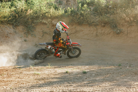 Dnipro, Ukraine JULY 01, 2022. Ukrainian beginner motorcycle rider driving on Enduro motorbike, outdoors at hot summer day. Kids motocross trainingのeditorial素材