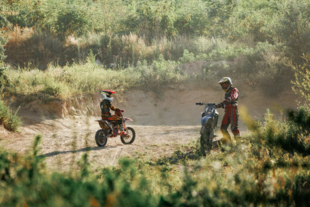 Dnipro, Ukraine JULY 01, 2022. Ukrainian beginner motorcycle rider driving on Enduro motorbike, outdoors at hot summer day. Kids motocross trainingのeditorial素材