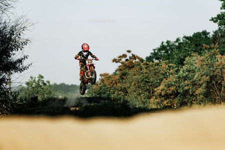 Dnipro, Ukraine JULY 01, 2022. Ukrainian beginner motorcycle rider driving on Enduro motorbike, outdoors at hot summer day. Kids motocross trainingのeditorial素材