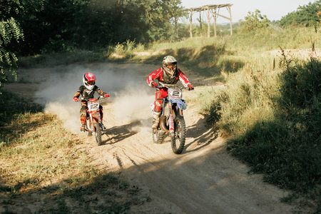 Dnipro, Ukraine JULY 01, 2022. Ukrainian beginner motorcycle rider driving on Enduro motorbike, outdoors at hot summer day. Kids motocross trainingのeditorial素材