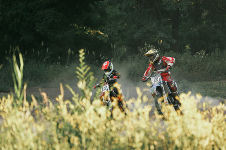 Dnipro, Ukraine JULY 01, 2022. Ukrainian beginner motorcycle rider driving on Enduro motorbike, outdoors at hot summer day. Kids motocross trainingのeditorial素材