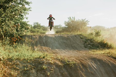 Dnipro, Ukraine JULY 01, 2022. Ukrainian beginner motorcycle rider driving on Enduro motorbike, outdoors at hot summer day. Kids motocross trainingのeditorial素材