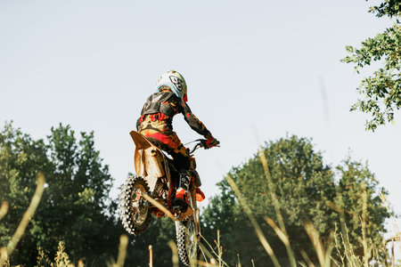 Dnipro, Ukraine JULY 01, 2022. Ukrainian beginner motorcycle rider driving on Enduro motorbike, outdoors at hot summer day. Kids motocross trainingのeditorial素材