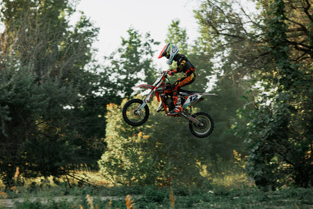 Dnipro, Ukraine JULY 01, 2022. Ukrainian beginner motorcycle rider driving on Enduro motorbike, outdoors at hot summer day. Kids motocross trainingのeditorial素材