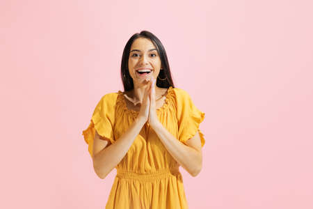 Happy young beautiful girl, student in summer yellow dress isolated on pink background. Concept of beauty, art, fashion, human emotionsの写真素材