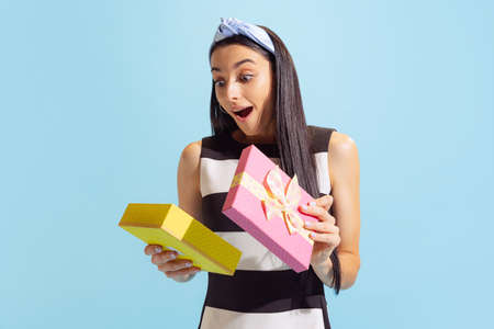 Thrilled young beautiful blond girl holding gift box isolated on blue background. Concept of...