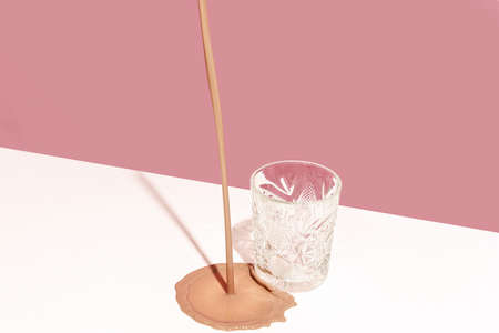 Delicious cocktail, milkshake, spilled on white tablecloth isolated over pink background. Pastel...