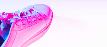 Closeup female sports shoes, sneakers isolated over neoned background. Urban city fashion, fitness, sport, training concept.の写真素材