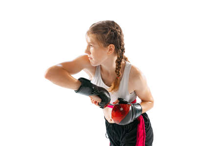 Junior female MMA fighter in sports uniform and gloves training isolated on white background. Concept of sport, competition, action, healthy lifestyle.の写真素材