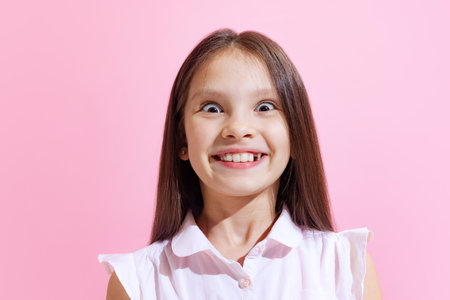 Emotional little charming girl, kid wearing blouse isolated on pink background. Concept of children emotions, fashion, beauty, school and adの写真素材