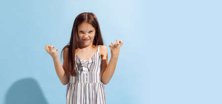 Annoyed school-age girl, kid in summer clothes posing isolated on light blue background. Concept of...