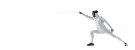 Dynamic portrait of young man, fencer in in fencing costume with sword in hand training isolated on white studio background. Sport, energy, skillsの写真素材