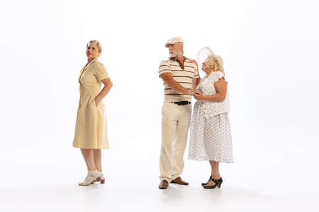Handsome senior man and two charming women in vintage retro style outfits isolated on white...