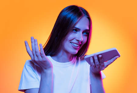 Half-length shot of emotional girl with long glossy dark hair isolated on orange background in neon...