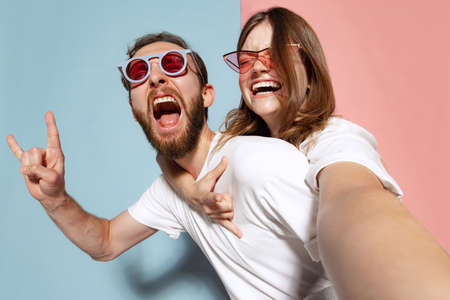 Portrait of crazy rock music fans, young couple wearing white t-shirts grimace and shout on...