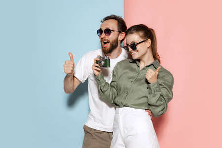 Astonished handsome man and charming girl smiling, gesturing isolated over blue-pink background. Fashion, emotions, youth, love, travel, vacation conceptの写真素材