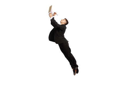 Sign contract. Young office worker in business suit jumping with papers isolated over white background. Finance, aspiration, business, job concept.の写真素材