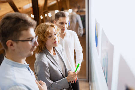 Group of happy, motivated young people discussing plans and projects. Coworkers working at office,...