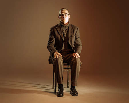 Retro style portrait of young man, writer and traveler wearing vintage style clothes isolated over dark brown background. Business, art, fashion conceptの写真素材