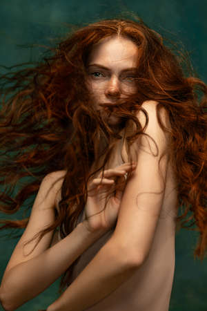 Portrait of sensual beautiful redhead girl with long curly hair. Gorgeous hair and deep green eyes. Concept of beauty, art, fashion, health and wellbeingの写真素材