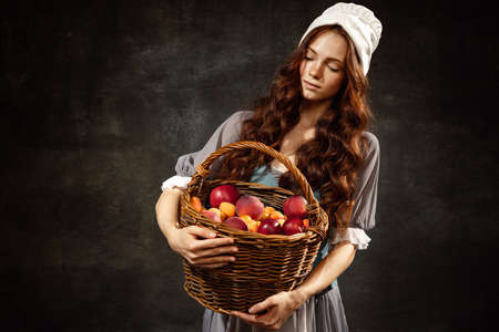 Portrait of charming redhair girl with long curly hair like girl of renaissance eras, lady-peasant isolated on dark background. Eras comparison, beauty, art,の写真素材