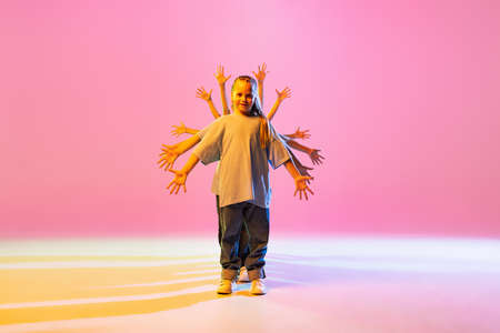 Dance group of happy, active little girls in t-shirts and jeans in action isolated on orange...