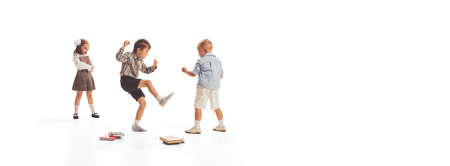 Portrait of little children, boys and girl, pupil in school uniform playing together on lessons break isolated over white backgroundの写真素材
