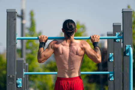 Lifestyle portrait of athlete, muscular shirtless man workout at sports ground at public park in summer morning, outdoors. Action, skills, challengesの写真素材