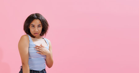 Flyer with pretty girl wearing summer striped tank top looking at camera with surprise isolated on pink background. Beauty, art, fashion, emotions conceptの写真素材