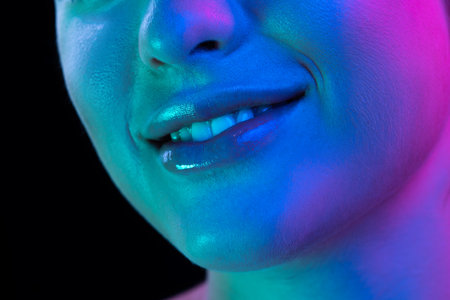 Closeup female lips, cheeks and nose isolated over dark background in neon light. Concept of cosmetology, skincare, cosmetics, plastic surgery, adの写真素材