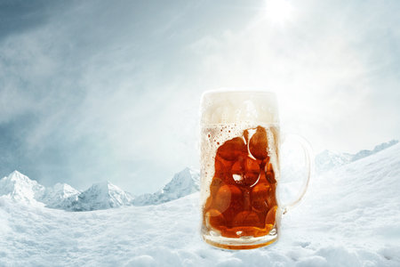 Poster with mug of light cold foamy beer over snow-capped mountains background. Holidays, vacation, drinks, taste, ad and oktoberfest conceptの写真素材